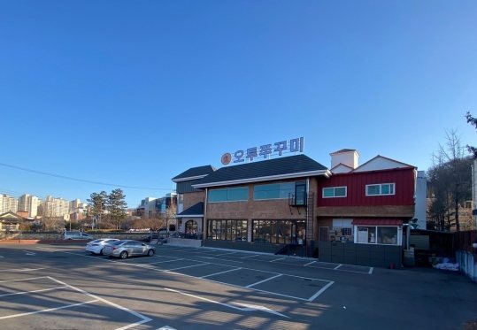 넓은 주차장 너머로 보이는 가게 건물(맑은 날)
